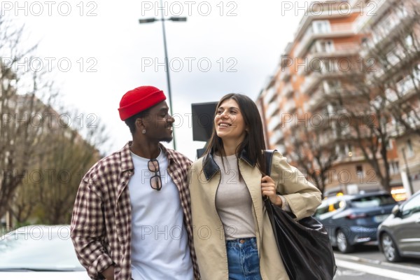Interracial couple smiling and walking down a vibrant city street, sharing a candid moment of joy, connection and togetherness during a casual daytime stroll