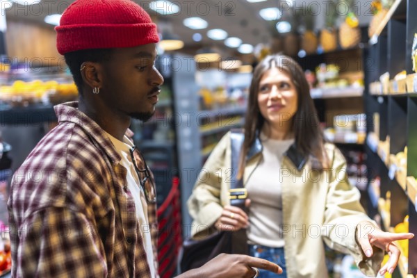 Diverse young couple selecting fresh produce in a modern supermarket aisle, comparing options and enjoying a healthy daily shopping routine together with smiles and casual conversation
