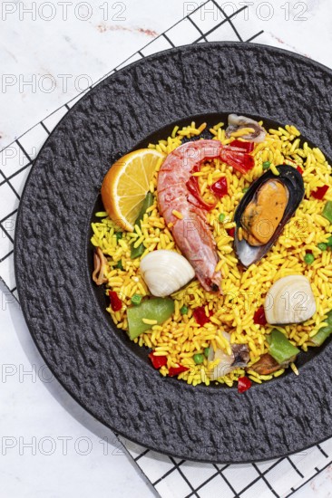 Seafood paella on a black plate, no people