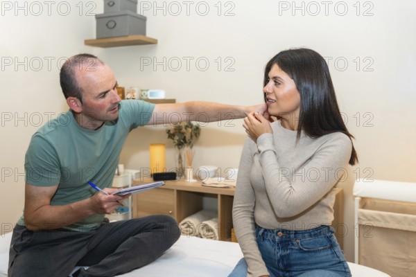 Physiotherapist consulting with a young female patient, carefully examining her neck and shoulder area in a clinic, focusing on diagnosis and treatment for discomfort