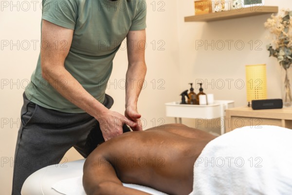 Professional therapist giving a relaxing back massage to a client lying face down on a treatment table, promoting wellness and stress relief in a serene spa setting