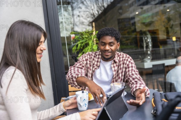Diverse friends discussing and working together on a modern digital tablet while enjoying coffee at an outdoor cafe, embodying teamwork and connectivity