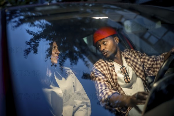 Interracial couple sharing a thoughtful conversation in a car at night, capturing authentic connection during an evening urban date that reflects modern, diverse relationships