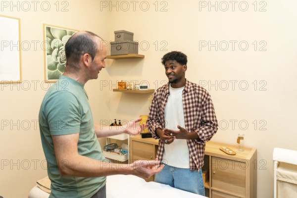 Two men engaging in a friendly and professional conversation about health and wellness, consulting with a specialist in a bright, modern clinic setting during their therapy appointment