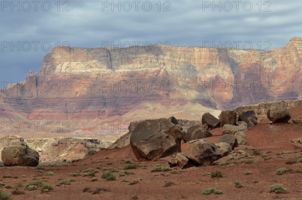 Large rocks spread across an impressive red desert landscape with dramatic skies, Grand Canyon National Park, Arizona, USA