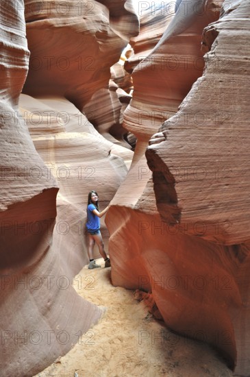 Girls in a narrow part of a sandstone canyon surrounded by bright orange rock walls, Antelope Canyon, Navajo Nation Reservation, Lake Powell Tribal Park, Arizona, USA