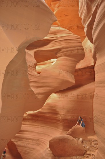 Rocky sandstone gorge in shades of orange with one person surrounded by smooth, lively rocks, Antelope Canyon, Navajo Nation Reservation, Lake Powell Tribal Park, Arizona, USA