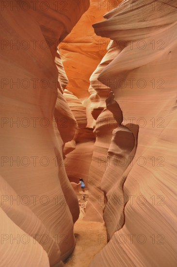 Person in a deep, wavy sandstone gorge with bright shades of orange, Antelope Canyon, Navajo Nation Reservation, Lake Powell Tribal Park, Arizona, USA