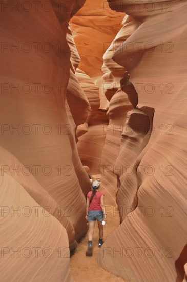 Person wandering through a narrow, winding canyon of orange sandstone, Antelope Canyon, Navajo Nation Reservation, Lake Powell Tribal Park, Arizona, USA