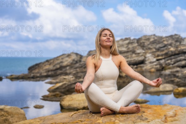 Woman in yoga pose on rocky coastline by the sea, practicing mindfulness and breathing for calm, balance and wellness amid serene ocean horizon and natural light