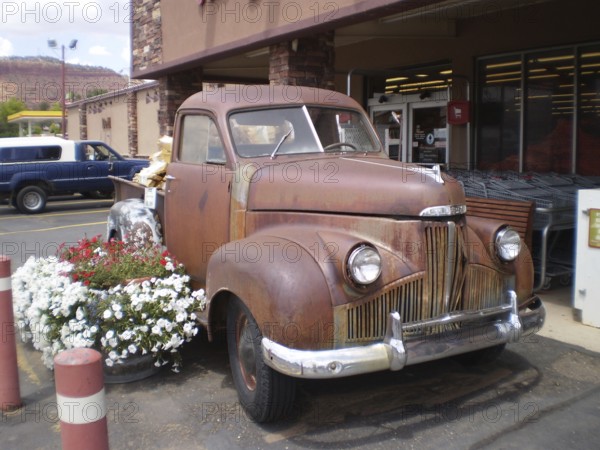 Nostalgic, rusty Studebaker pick-up truck with flower decoration in front of the Honey's Marketplace store, Zion National Park, Utah, USA