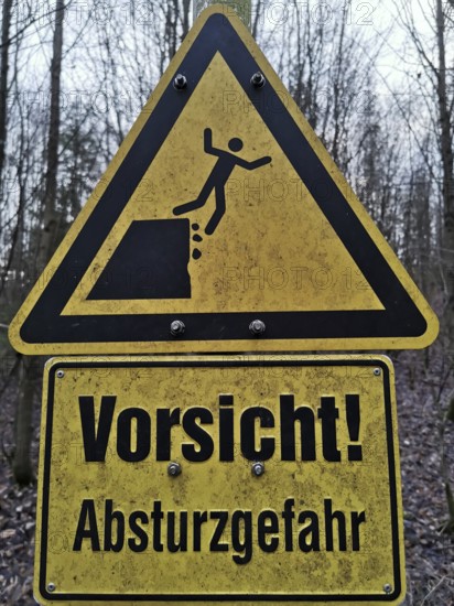 Yellow warning sign in the forest with an indication of the risk of falling, quarry, Frankenwald nature park Park