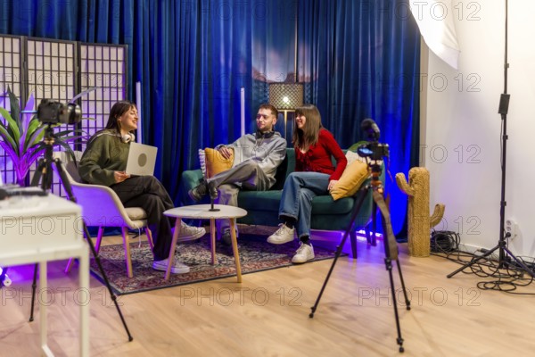 Group of young content creators smiling and interacting while recording a podcast or video interview in a modern studio setup with professional equipment