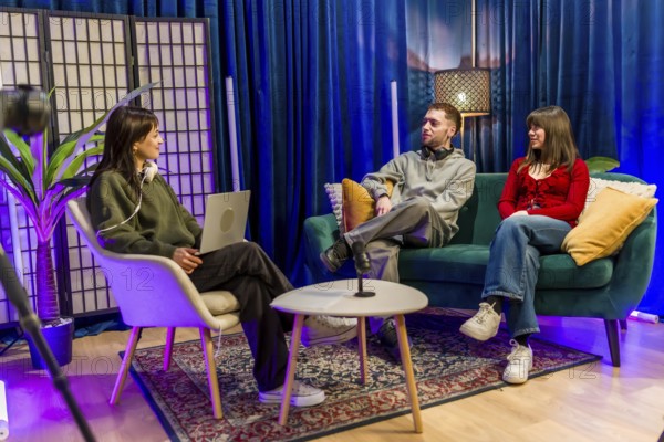 Young men and women are collaborating and talking in a colorful studio setting, recording a podcast or social media content using professional equipment