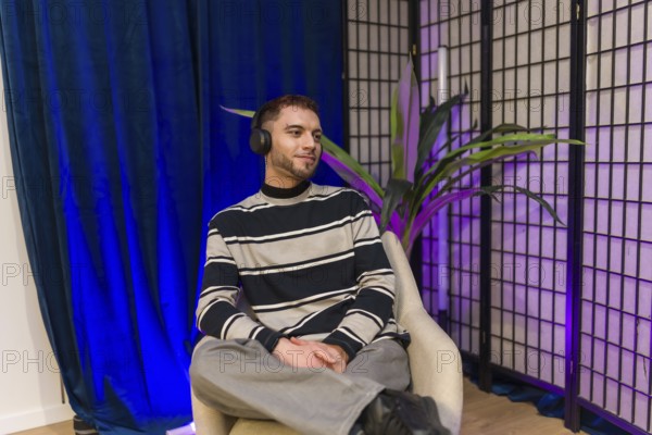 Young content creator wearing headphones, sitting in a modern studio setup, preparing for a podcast recording session or producing social media video material