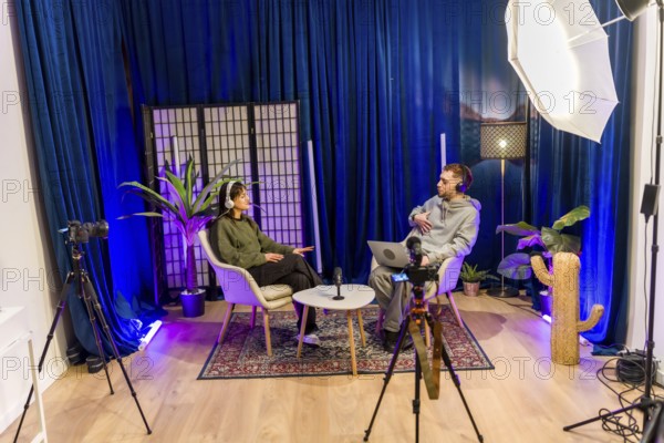 Young diverse people recording a social media podcast in a professional studio, creating digital content for online platforms with microphones, cameras, and lighting equipment