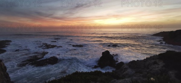 Sunset over the sea, gentle waves and rocks in a tranquil atmosphere, hiking on the Fisherman's Trail, Southwest Alentejo nature park Park and Vicentina Coast, Portugal