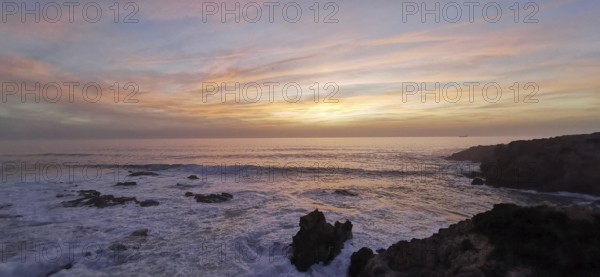 Pastel-coloured sunset over the sea. The light of the sky is reflected gently over the waves, hiking on the Fisherman's Trail, Southwest Alentejo nature park Park and Vicentina Coast, Portugal