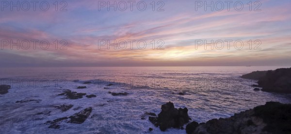 Romantic sunset over the sea with pink sky and dark rocks, hiking on the Fisherman's Trail, Southwest Alentejo nature park Park and Vicentina Coast, Portugal