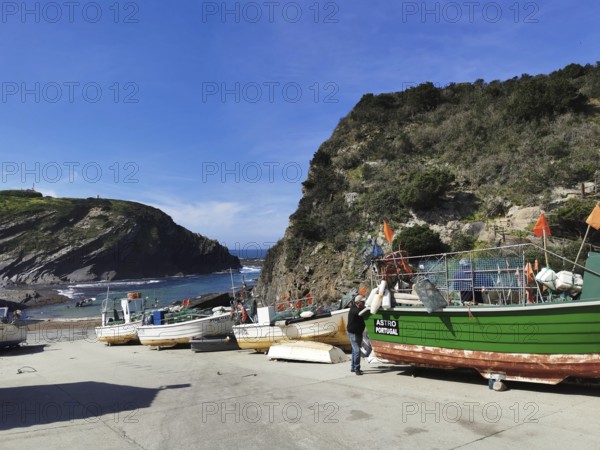 Small harbor with colorful fishing boats against a rocky coastal backdrop, hiking on the Fisherman's Trail, Lagos, Algarve, Portugal