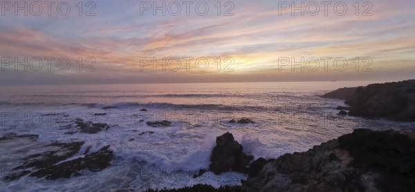 A gentle sunset with pastel-colored sky over the roaring sea, hiking the Fisherman's Trail, Southwest Alentejo nature park Park and Vicentina Coast, Portugal