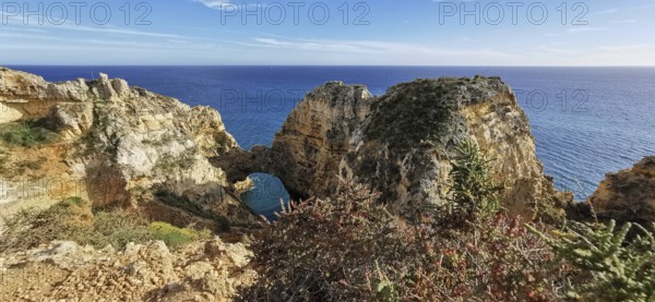 Archway, vast rocky landscape on the edge of the sparkling blue ocean, Lagos, Algarve, Portugal