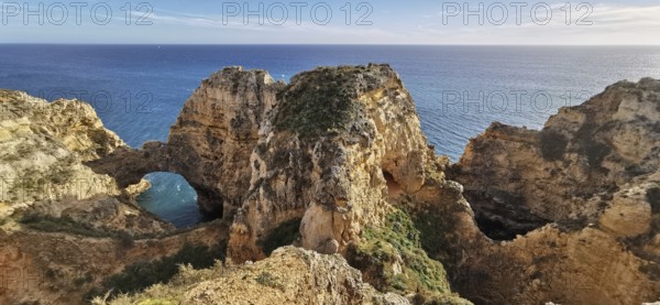 Archway, Dramatic rock formations overlooking the vast ocean under blue sky, Lagos, Algarve, Portugal