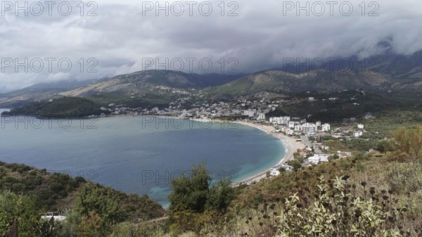 Coastal town in a bay surrounded by mountains and under a cloudy sky, Himare, Albanian Riviera, Albania