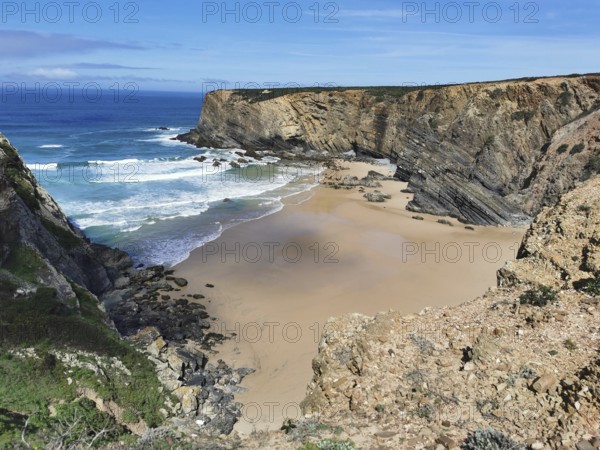 Secluded bay with golden sandy beaches and breaking waves between steep cliffs, hiking on the Fisherman's Trail, Algarve, Portugal