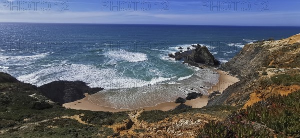 Waves break on a secluded sandy beach surrounded by rocks under a clear sky, hiking the Fisherman's Trail, Algarve, Portugal