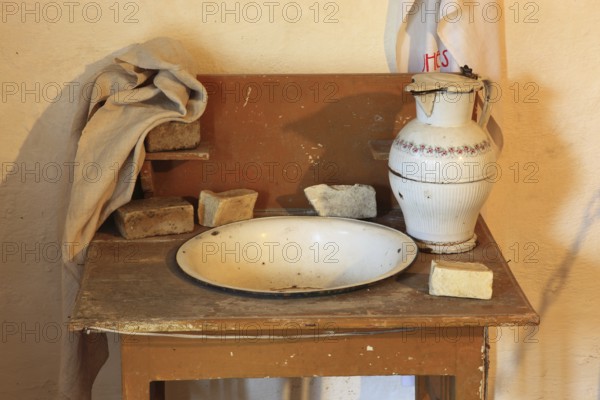 Antique washbasin with accessories, as used around 1900 in rural areas for daily body care. A large, white enameled or ceramic jug and a washing bowl, Lavoir, museum within the fortified church of Honigberg, Biserica Fortificata Harman, Transylvania, Romania