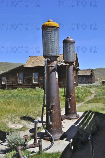 Two rusty old gas pumps, gas station, in front of a historic wooden building under a blue sky, Bodie Ghost Town, California, USA