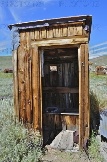 An old, rustic wooden cabin, toilet, outhouse, in historic construction in a rural area, Bodie Ghost Town, California, USA