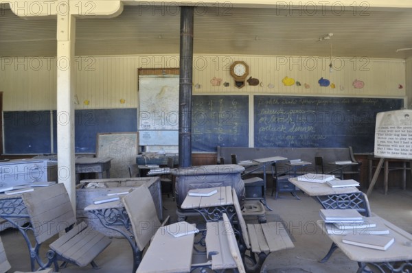 An old abandoned schoolroom with antique benches, chalkboards and open books, Bodie Ghost Town, California, USA