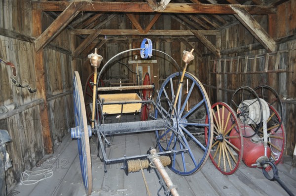 Antique tools and wagons in an old, abandoned wooden barn, fire engines, Bodie Ghost Town, California, USA