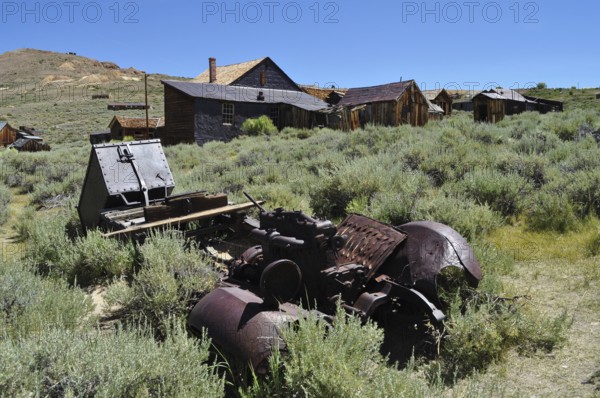 Abandoned wooden houses in mountainous area with rusty car wreck, Bodie Ghost Town, California, USA
