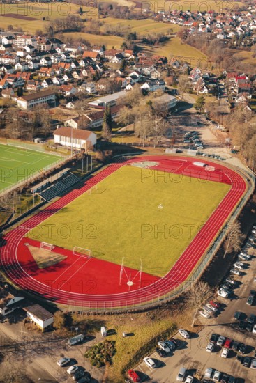 Sports field with red track and surrounding urban area seen from the air, Wimberg, Calw, Germany