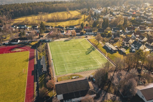 Village with sports field, soccer field and surrounding houses and landscape viewed from the air, Wimberg, Calw, Germany