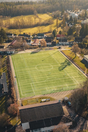 Green soccer field in rural area with surrounding trees and buildings, seen from the air, Wimberg, Calw, Germany
