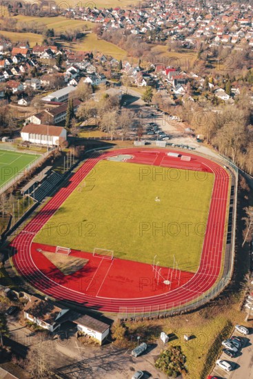 Sports field with red track and green field in a rural village seen from the air, Wimberg, Calw, Germany