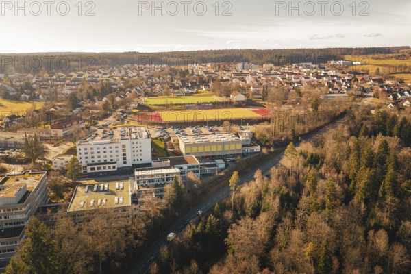Extensive view of an urban landscape with schools, sports facilities and surrounding forests in a winter landscape, Wimberg, Calw, Germany