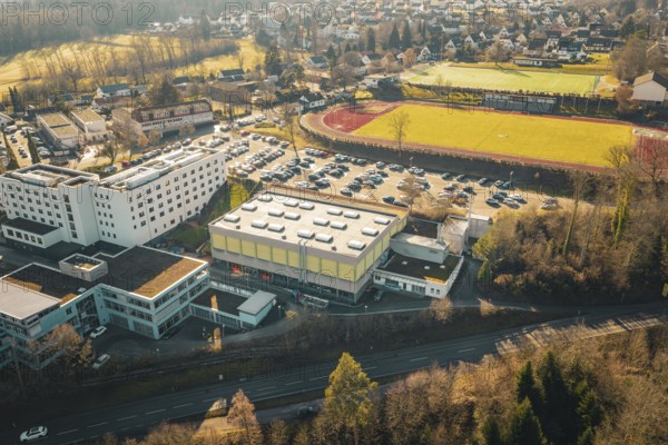 Aerial view of a city with buildings, sports ground and parking lot in sunny landscape, Wimberg, Calw, Germany