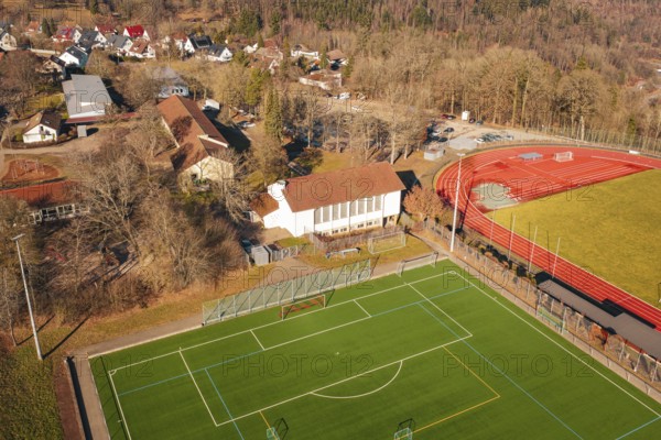 Aerial view of a sports field with red running track and nearby buildings in a village, Wimberg, Calw, Germany