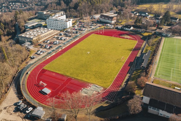 Sports ground with red track and adjacent buildings and parking spaces from the air, Wimberg, Calw, Germany