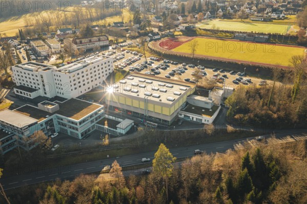 View of a school complex with sports hall, several parked cars and adjacent nature in a wintry atmosphere, Wimberg, Calw, Germany