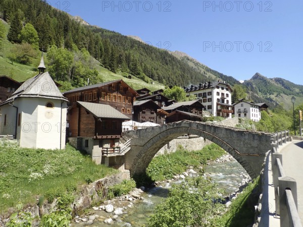 Mountain village with picturesque stone bridge and river in alpine landscape with clear sky, Binn, Binn Valley, Goms, Canton of Valais, Switzerland
