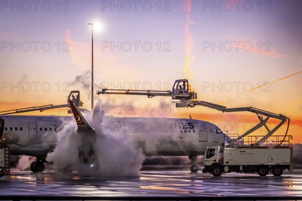 Frost at the airport in front of sunrise. A Turkish Airways aircraft is de-iced. Airbus A321-231. Fraport airport. Frankfurt am Main, Hesse, Germany