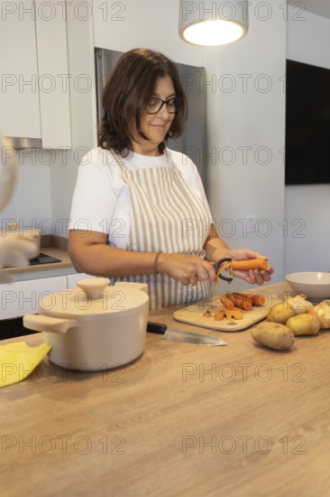 Vertical composition of woman preparing fresh vegetables on kitchen counter. Cozy domestic atmosphere, healthy ingredients and casual home cooking concept