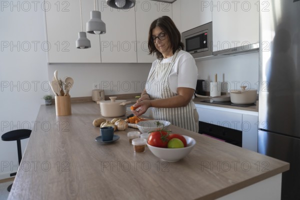 Woman peeling carrots and preparing vegetables for healthy homemade meal in modern kitchen. Clean eating and simple cooking concept