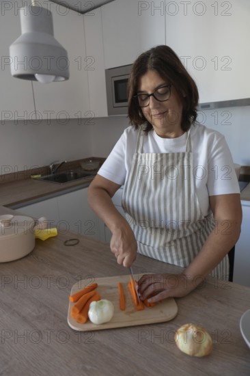 Woman cutting fresh carrots and preparing vegetables for healthy homemade meal in modern kitchen. Clean eating and simple cooking concept